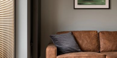 Cozy living room with brown leather sofa and abstract wall art.