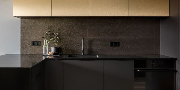 Modern kitchen with dark cabinets and golden upper cupboards.
