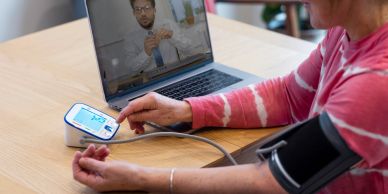 Person checking blood pressure during online consultation.