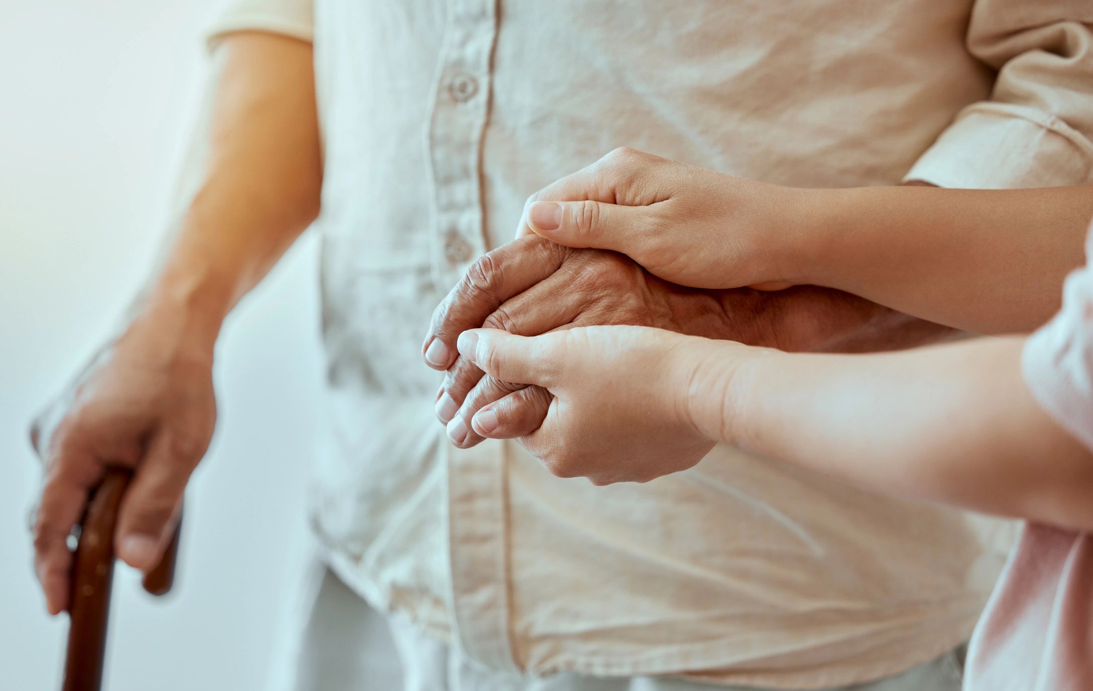 Younger hands gently holding an elderly hand for support and care.