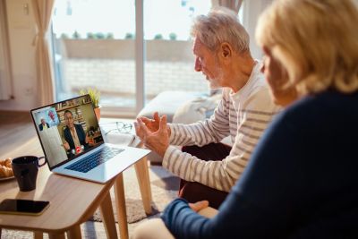 Elderly couple video calling a professional on a laptop.