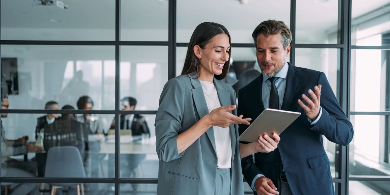 Dos profesionales conversan y usan una tableta en la oficina.
