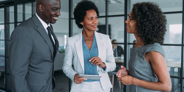 Three professionals engaged in a friendly office conversation.