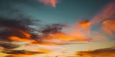 Silhouettes of people watching a vibrant sunset over the ocean.