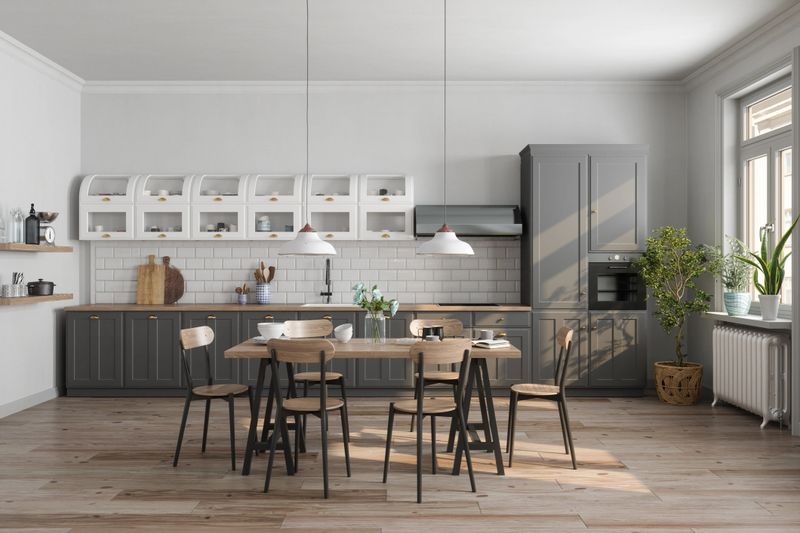 Modern Kitchen Interior With Gray Cabinets, Wooden Table, Chairs And Houseplants