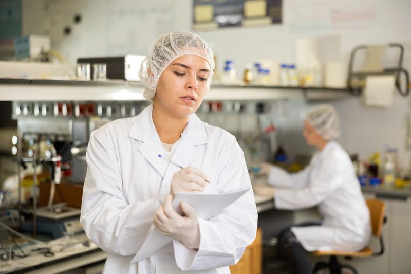 Professional scientist woman writing notes or research report during experiment in science laboratory