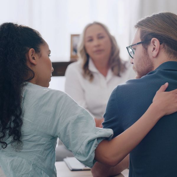 A woman comforts a man during a counseling session with a therapist.
