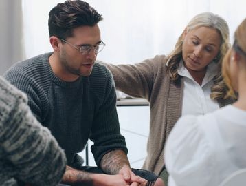 Woman consoling man during group therapy session.