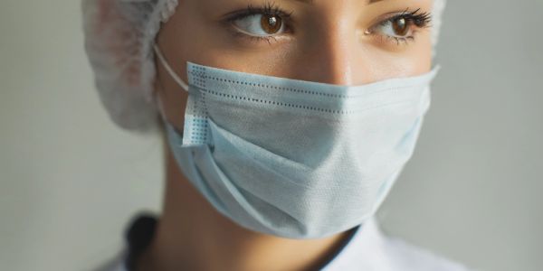 Close-up of a woman wearing a surgical mask and hairnet.