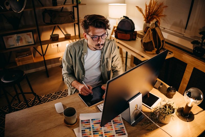 Young handsome man working late at night in his home office