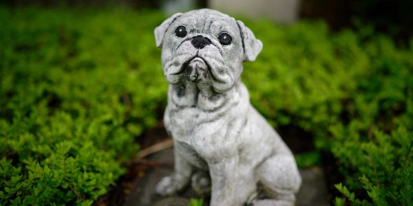 Gray bulldog statue in garden.