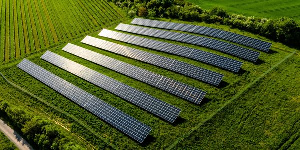 Aerial view of solar panels arranged in rows on green farmland.