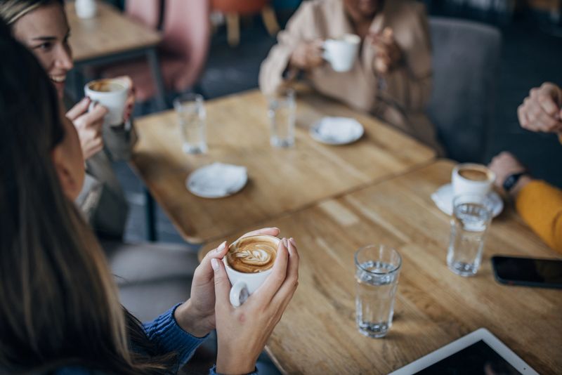 Diverse people, modern male and female friends sitting together on coffee in coffee shop.