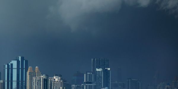 City skyline under a dramatic, dark stormy sky.