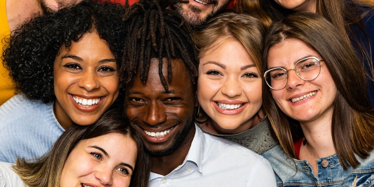 Group of diverse friends smiling closely together for a photo.