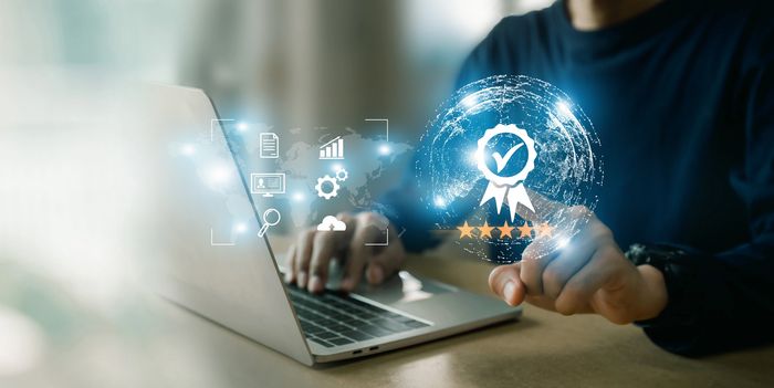 Person using a laptop with a digital quality certification and rating hologram.