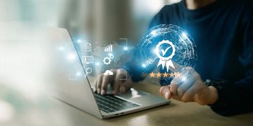Person interacting with digital quality assurance icons above a laptop.