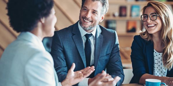 Three professionals engaged in a friendly business discussion.