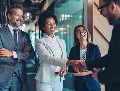 Business professionals smiling and shaking hands in an office.