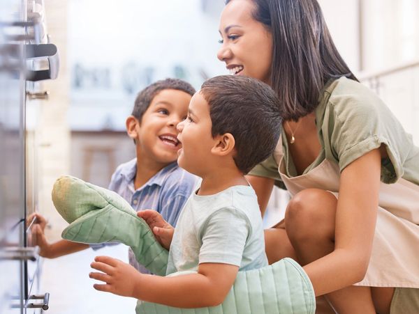 Mother and two young boys happily baking together in the kitchen.