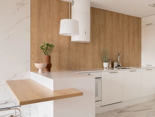 Modern kitchen with white cabinets, wood accents, and marble flooring.