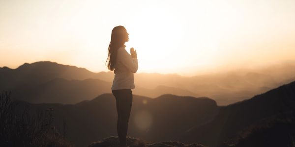 Person meditating at sunrise in the mountains.