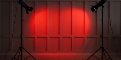 Two lights shining red on a paneled wall.