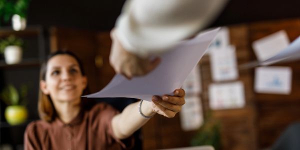 Person handing over papers with a smile.