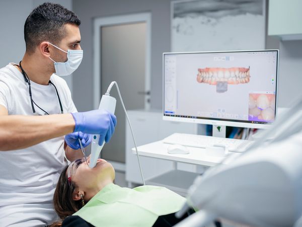 Dentist using digital scanner for dental imaging on patient.