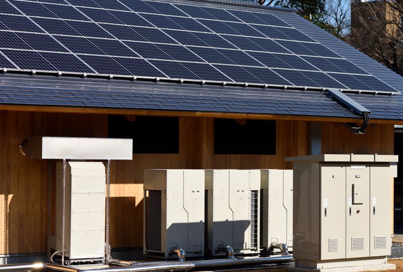 Solar panels installed on a rooftop with energy storage systems next to them.