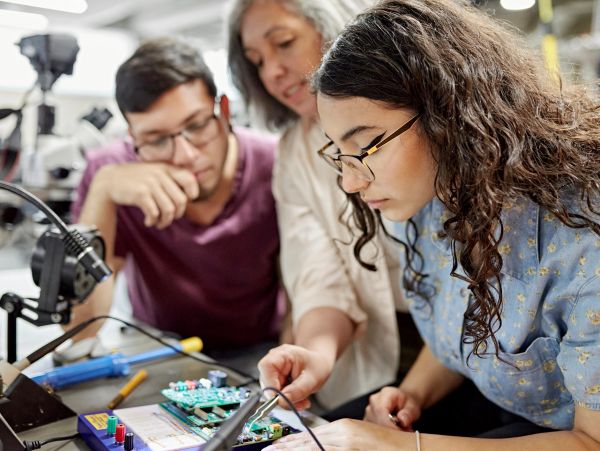 Three people working on electronic components.