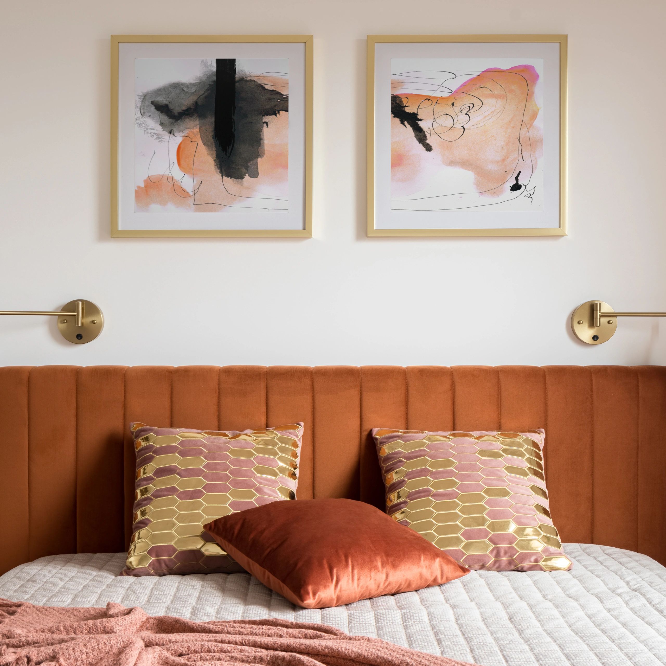Cozy bedroom with rust-colored headboard and abstract art.