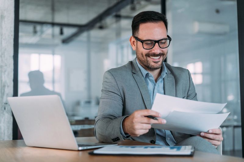 Shot of smiling businessman reading a document at his desk in an office.