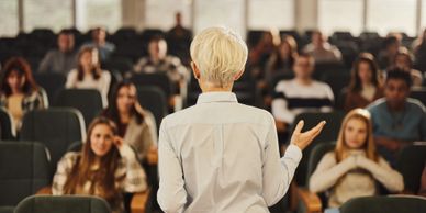 A person giving a lecture to an attentive audience in a classroom.
