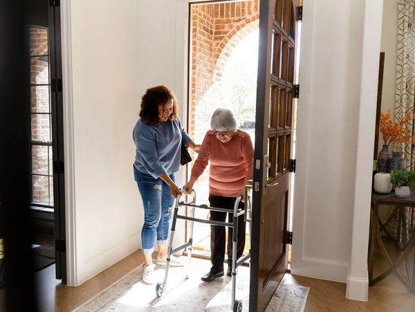 Caregiver assisting senior with walker.