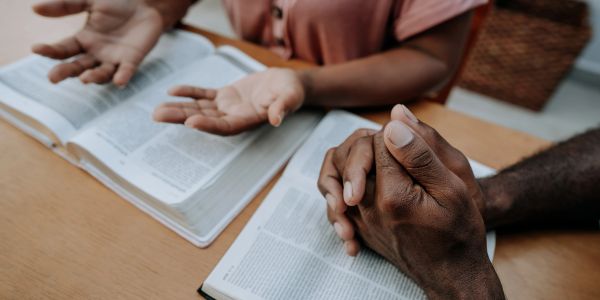 Two people praying over open books.