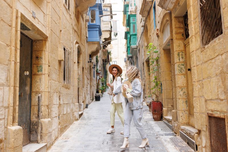 Cheerful female friends exploring old Mediterranean town on sunny day