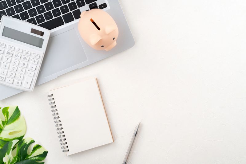 Annual financial budget and saving plan design concept with laptop, piggy bank, calculator and notebook with copy space on white table background.