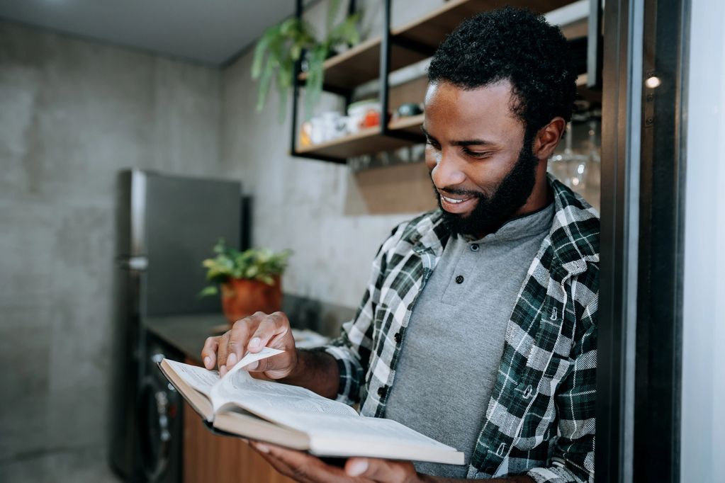 Man reading a book in a kitchen.