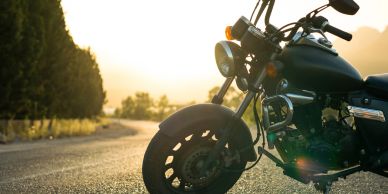 Motorcycle parked on a sunlit road during sunset.