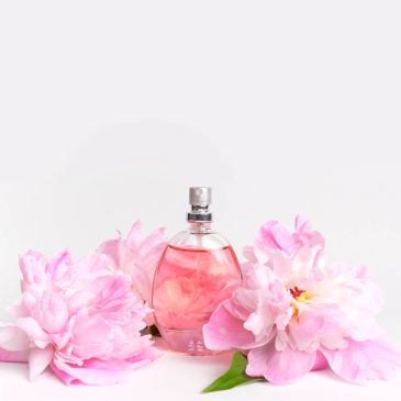 Perfume bottle surrounded by pink flowers.