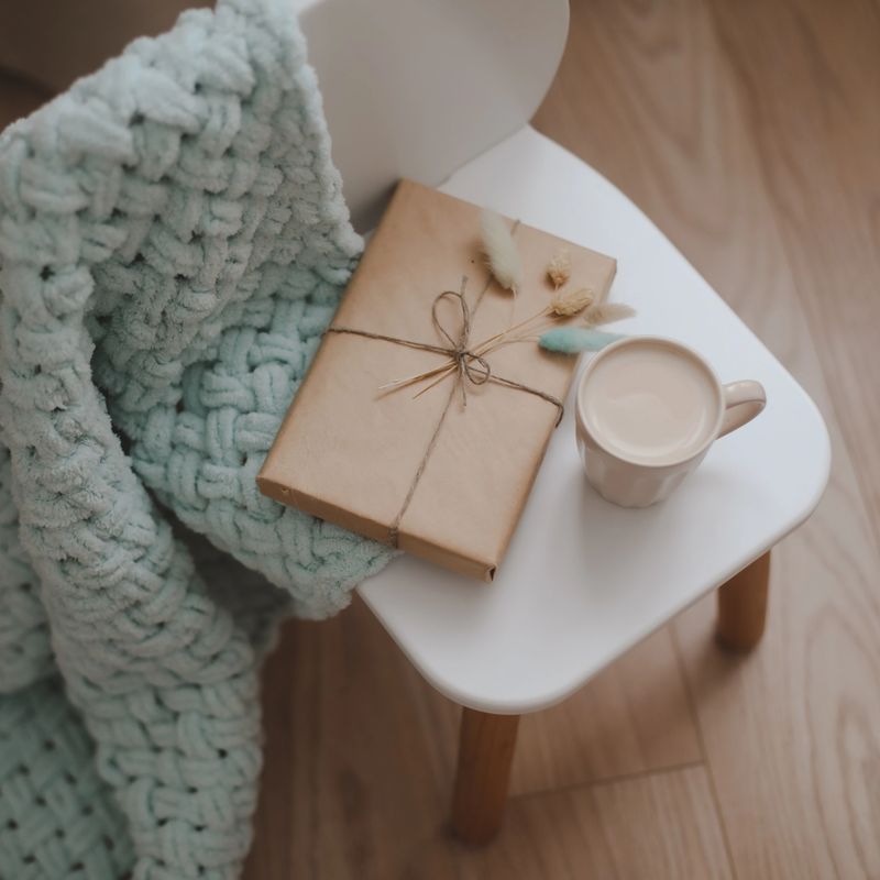 Composition with a gift, book, cup of coffee and plaid top view.