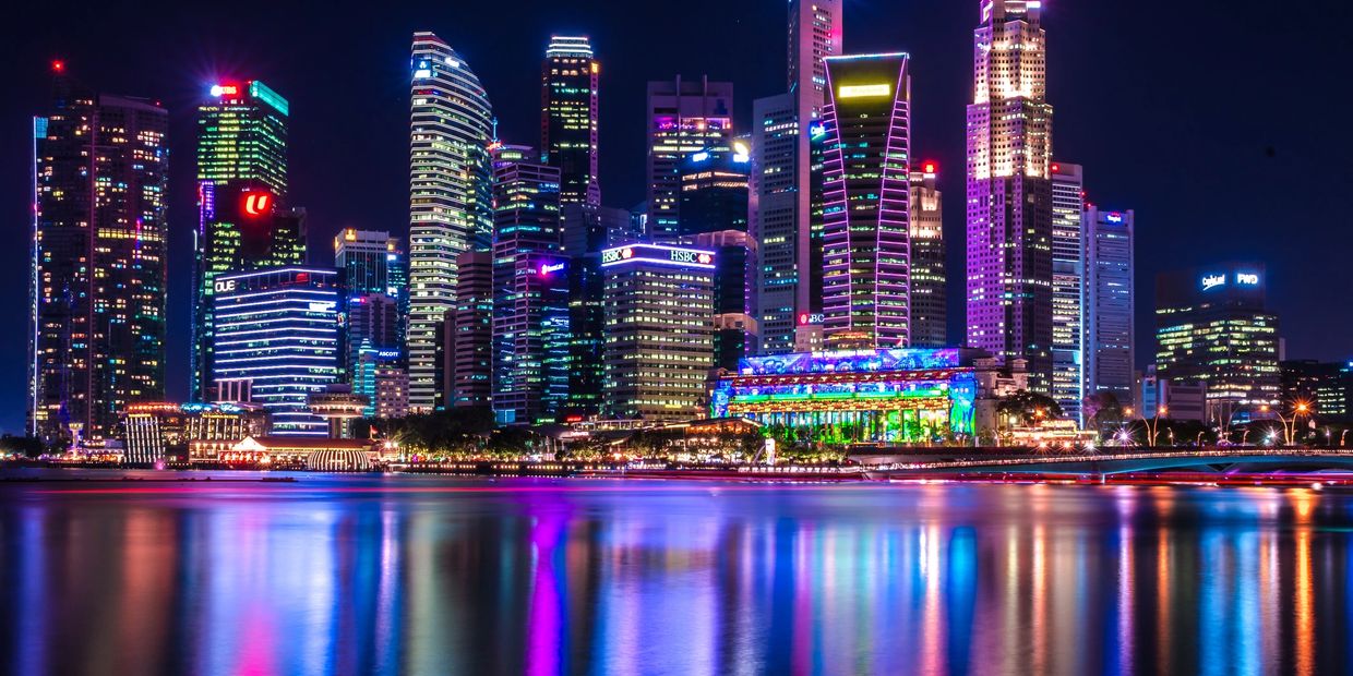 Vibrant city skyline at night with colorful reflections on the water.