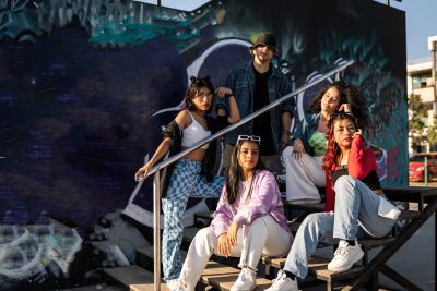 Five young adults posing on outdoor stairs.