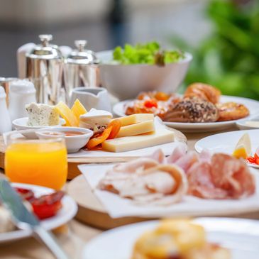 hotel food, including a glass of orange juice, meats, cheeses and salad.