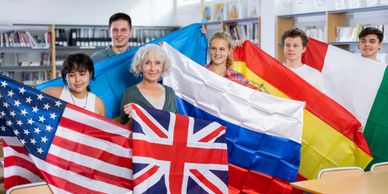 A diverse group of people holding various international flags in a library.