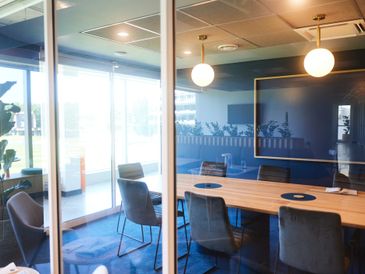 Modern conference room with glass walls and comfortable chairs.