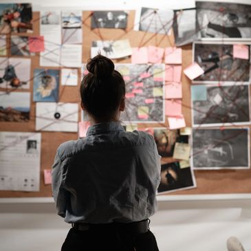 Person analyzing a complex investigation board filled with photos and notes.