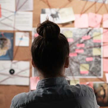 Person studying complex clues on a case board.