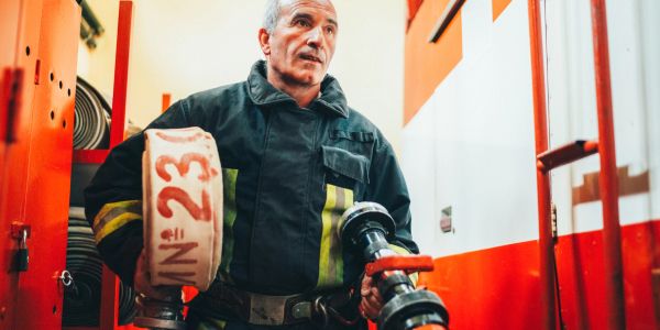 Firefighter holding a fire hose labeled 'No 23'.